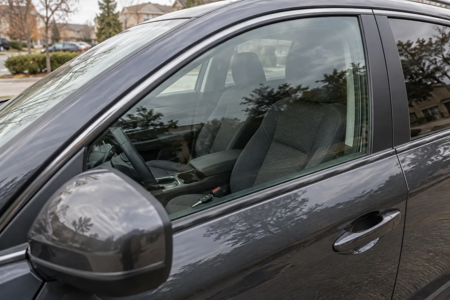 A key rests on the driver’s seat behind a closed car window